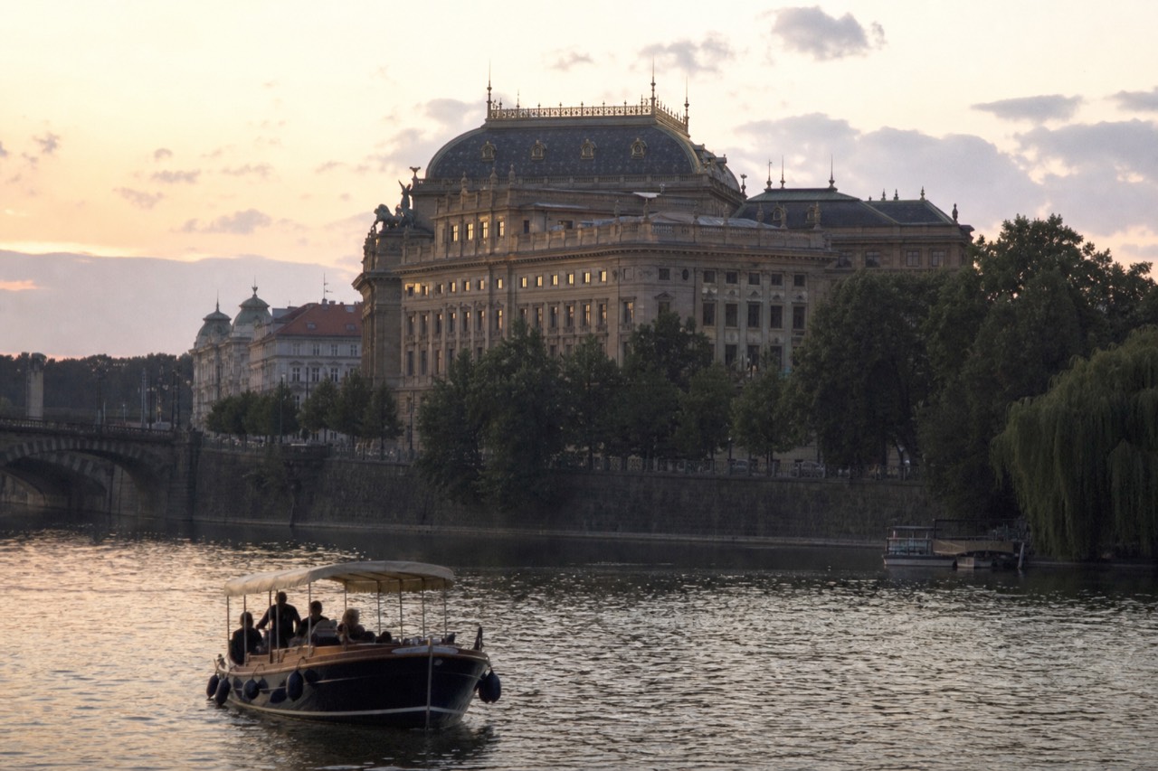 Evening view of the Vltava in Prague with the lit National Theatre and embankment reflected in the water