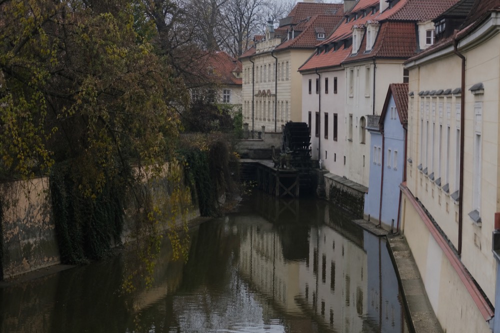 The narrow Čertovka canal between old timbered houses, still water holding soft reflections